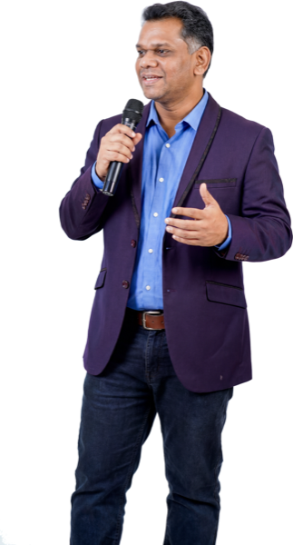 Shankar J speaking with a microphone on a white background, 1294 by 2400 pixels